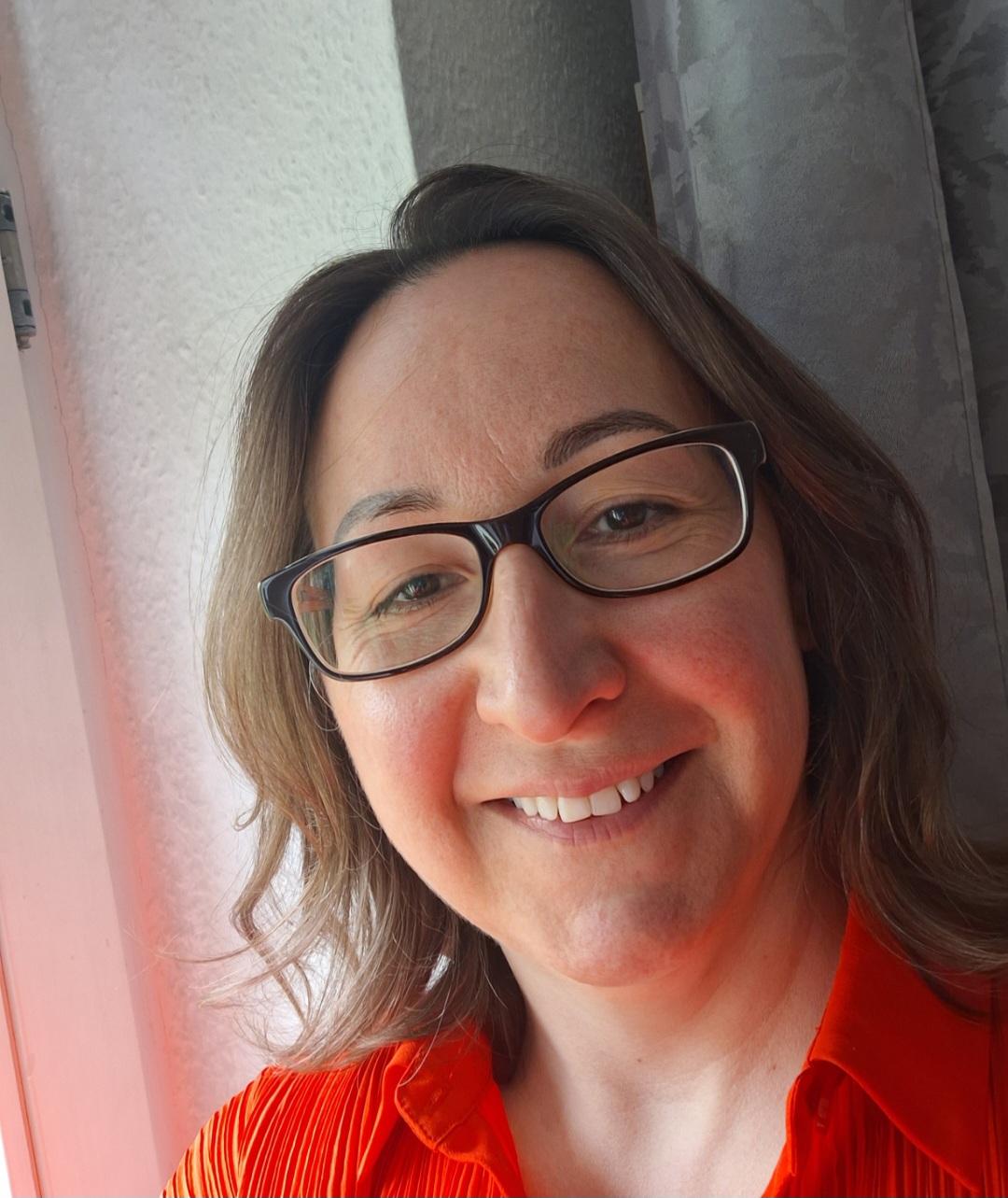 Porträt einer lächelnden Frau mit Brille.
